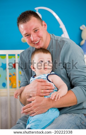 Portrait of baby boy ( 1 year old ) and father at children\'s room, smiling.