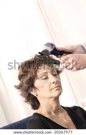 Senior woman having haircut in barber shop.