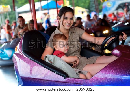 Mother and 2 years old baby pay drive dodgem together in the theme-park.