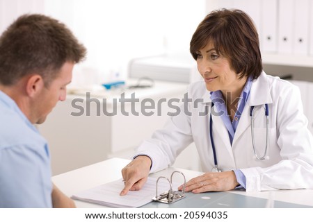 Smiling senior female doctor talking with male patient at office.