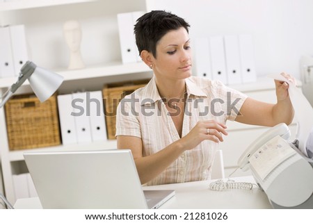 Woman using fax machine at home office.