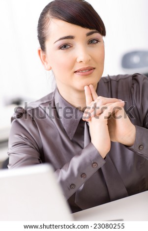 Young businesswoman thinking in her office, interlocking his hands.