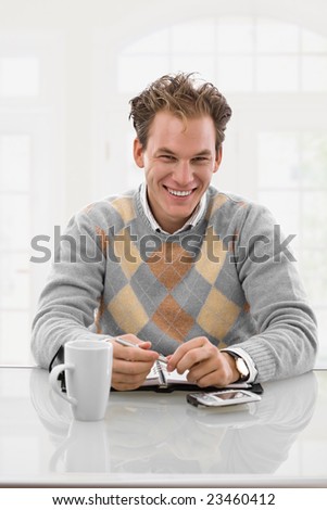 Happy young man working at desk at home, smiling.
