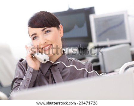 Young female customer service operator talking on landline phone, smiling.