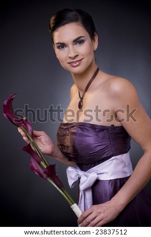 Studio portrait of a beautiful young woman wearing a light purple evening dress holdiing flowers in her hands.