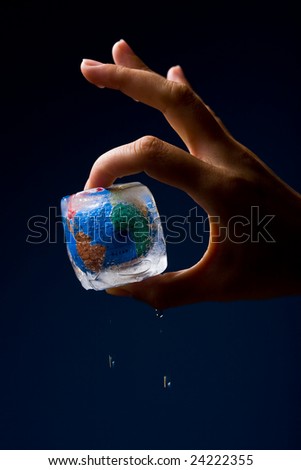 Conceptual image of global warming and green environmentalism. Human hand holding earth globe frozen into thawing ice cube.