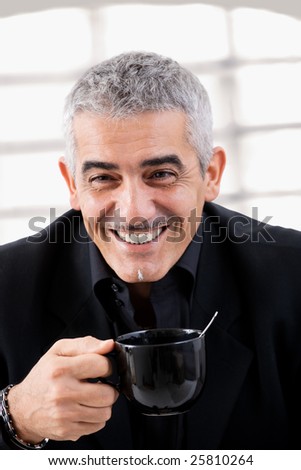 Happy mature businessman drinking tea, smiling.