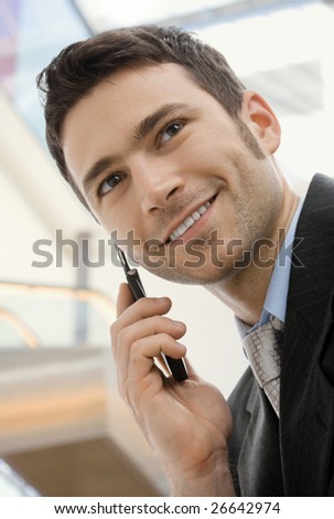 Young happy businessman calling on mobile phone, outdoor, smiling.