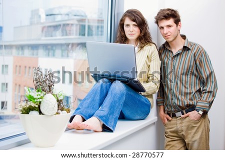 Male and female office workers talking and brainstorming at office, using laptop computer.