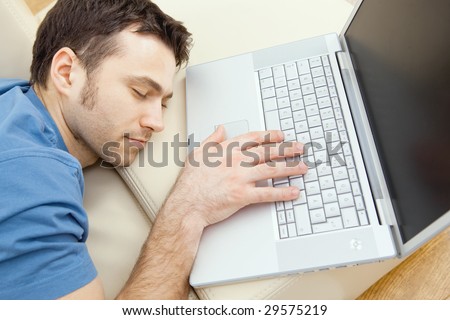 Man overslept by the keyboard of a laptop computer. eyes closed, high-angle view.