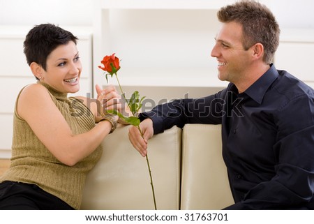 Romantic man giving red rose to woman for Valentine\'s Day.