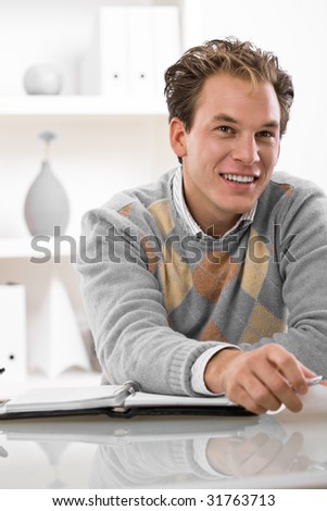 Happy young man working at desk at home.