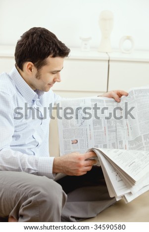 Handsome young man reading newspaper.