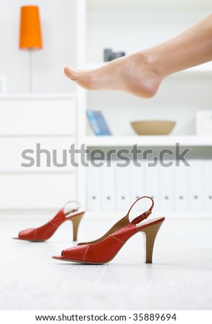 Woman legs in stockings, taking off high heel shoes.