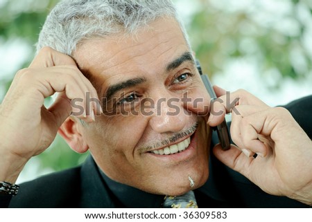 Gray haired mature businessman calling on mobile phone, smiling.
