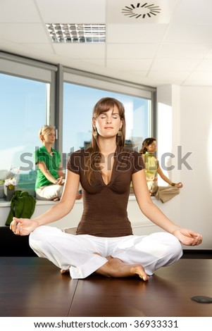 Young businesswomen sitting in yoga position in office.