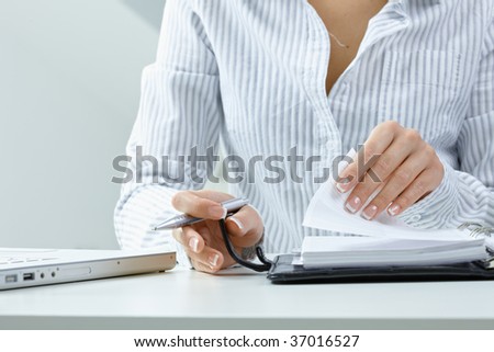 Woman turning a page of personal organizer, focus on hands.