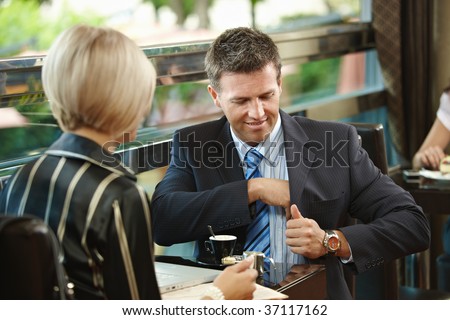 Young businessman and businesswoman sitting at table, having a meeting in cafe.