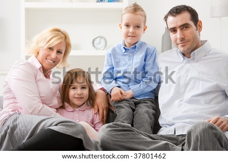 Happy family sitting together on sofa at home, smiling.