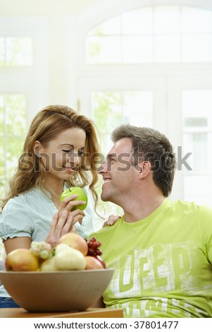 Love couple having breakfast together. Woman giving apple to her boyfriend.