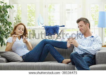 Couple relaxing at home on sofa, man giving foot massage to her gildfriend.