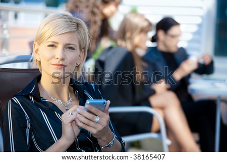 Young businesswoman using smart mobile phone, outside office building.