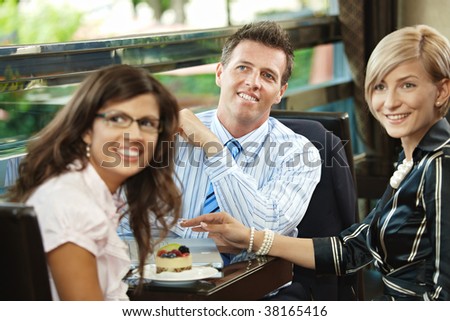 Young businessman and businesswomen having a meeting in cafe, smiling and greeting somebody.