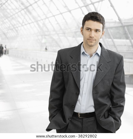 Portrait of tired businessman standing in office lobby after work, in open collar shirt without tie.