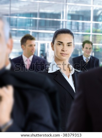 Young businesswoman standing amongt other businesspeople,in front of office building.