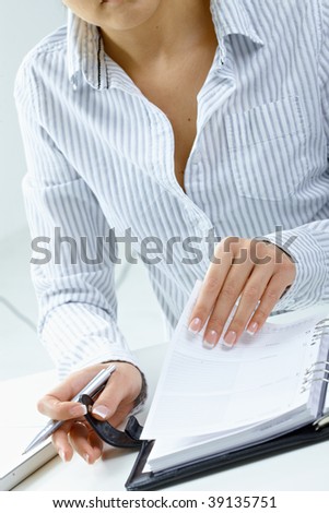 Woman turning a page of personal organizer, focus on hands.
