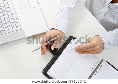 Female hands holding pen and turning a page of personal organizer.
