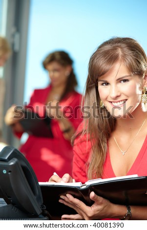 Closeup portrait of young businesswoman writing notes into personal organizer, smiling.