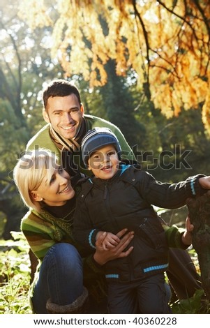 Happy family looking at camera, smiling outdoor in park at autumn. - stock photo