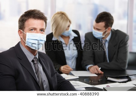 Businessman fearing h1n1 swine flu virus wearing protective face mask during meeting at office.