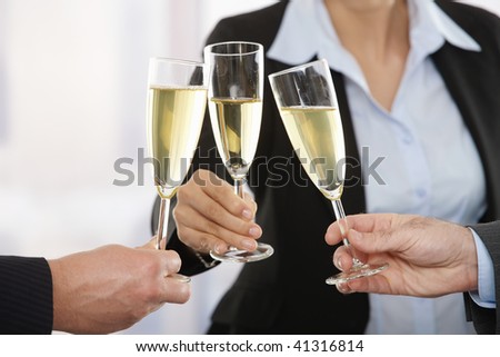 Close-up of hands: husiness people raising toast with champagne focus placed on flutes.