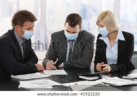 Business people fearing h1n1 swine flu virus wearing protective face mask during meeting at office.