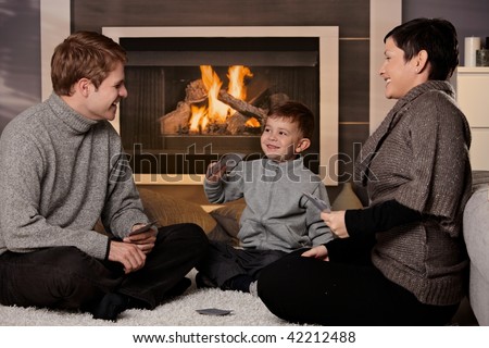 Young family with 4 years old kid playing card game at home in a cold winter day.