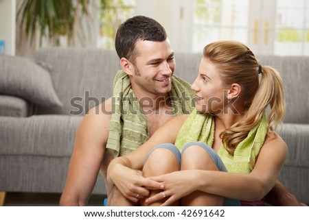 Portrait of young couple resting after training, looking at each other smiling.