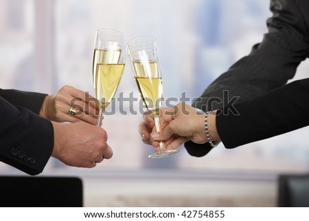 Close-up of hands: business people raising toast with champagne focus placed on flutes.
