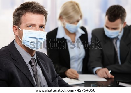 Businessman fearing h1n1 swine flu virus wearing protective face mask during meeting at office.