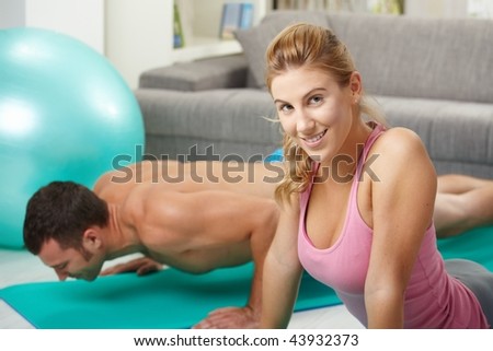 Young couple doing push up exercise at home in living room.