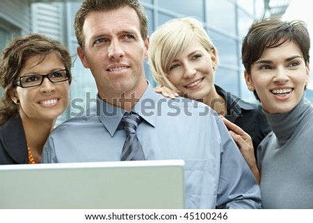 Team of business people looking at laptop computer outdoor in front of office building.