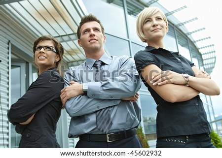 Group of dedicated young business people posing outdoor in front of office building.