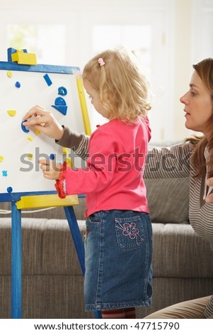 Little girl playing board game with mum in living room.