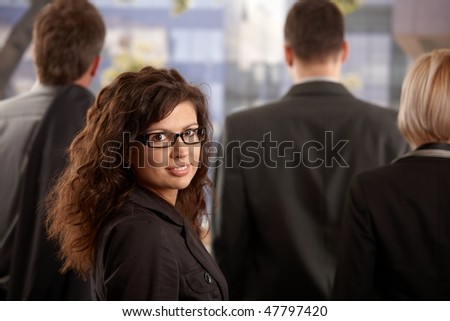 Business people leaving office at afternoon young businesswoman standing outdoor, looking back, smiling.