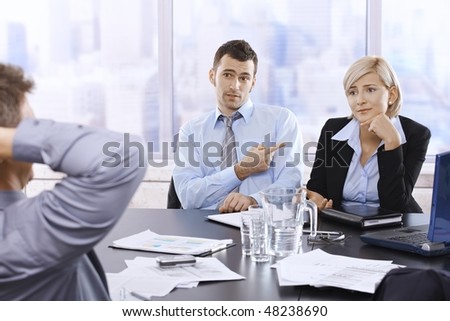 Troubled businesspeople in discussion at office meeting, businessman looking at boss blaming colleague.