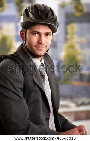 Portrait of young businessman wearing bike helmet, arriving to work at morning, smiling.