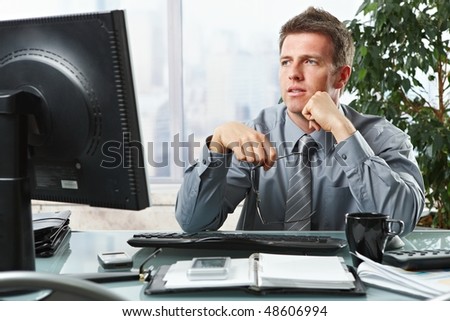 Confident businessman focusing on computer screen sitting at desk in office.