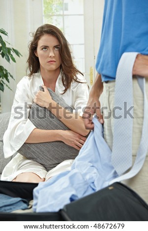 Unhappy couple breaking,  sad woman sitting on on couch hugging pillow.