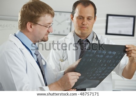 Medical office - middle-aged male doctors having consultation over computer tomograph scan.